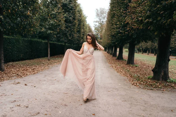 Joven hermosa mujer en larga rosa vestido de noche sendero caminando —  Fotos de Stock