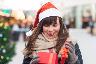 santa şapka hediye kutusu Noel pazarı üzerinde tutan güzel kadın