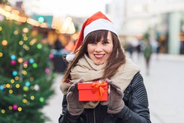 santa şapka hediye kutusu Noel pazarı üzerinde tutan güzel kadın