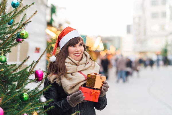 Mooie vrouw in KERSTMUTS houden twee huidige dozen op kerstmarkt — Stockfoto