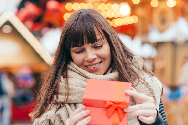 Beautiful woman holding a present box on a christmas market — Stock Photo, Image