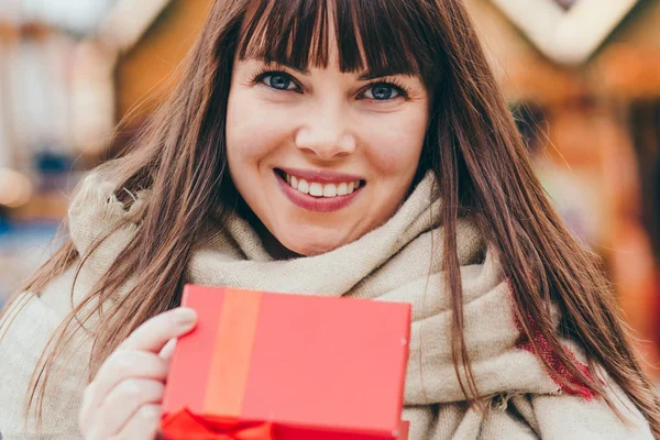 Beautiful woman holding a present box on a christmas market — Stock Photo, Image
