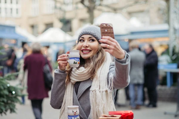 güzel kadın içecekler sıcak şarap ve bir benlik resmi Noel pazarı için yapar 