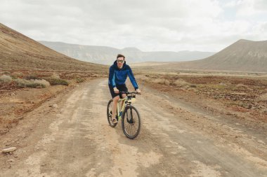 yakışıklı adam rahat kıyafet binmek kira ile bir dağ bisikleti üzerinde yazılı bir bisiklet 