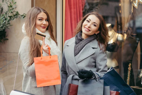 Dos chicas son felices con una tarjeta de crédito por las compras —  Fotos de Stock
