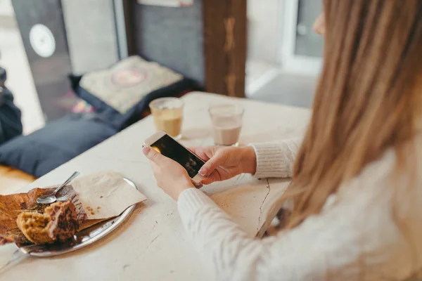 Händerna på en kvinna med en smart telefon i café — Stockfoto