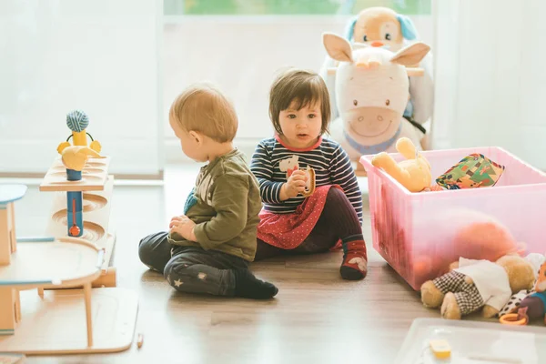 Menina e menino brincando com brinquedos pela casa — Fotografia de Stock