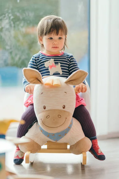 Menina balançando em um cavalo de balanço — Fotografia de Stock