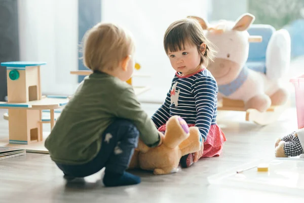Menina e menino brincando com brinquedos pela casa — Fotografia de Stock