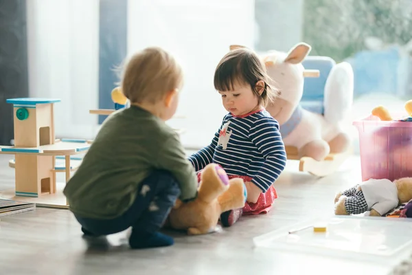 Menina e menino brincando com brinquedos pela casa — Fotografia de Stock