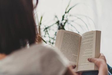 Güzel bir kadın evde kitap okuyor.