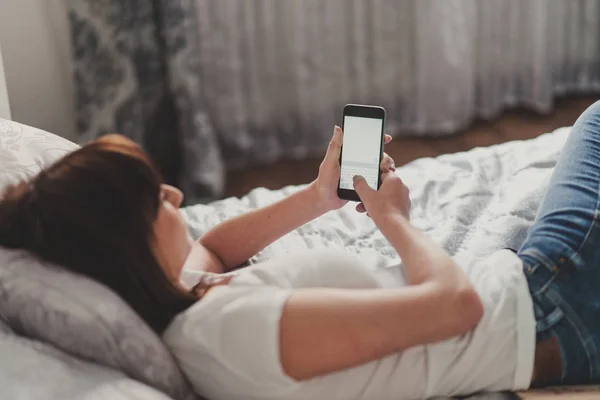 Vacker kvinna skriver sms på smartphone i vit tshirt — Stockfoto