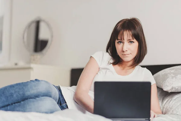 Schöne Frau arbeitet am Laptop im Schlafzimmer — Stockfoto