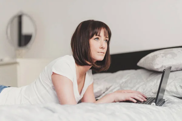 Vacker kvinna fungerar på laptop i sovrummet — Stockfoto