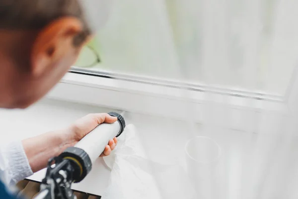 Retrospectiva del anciano usando un tubo de silicona para reparar la ventana —  Fotos de Stock