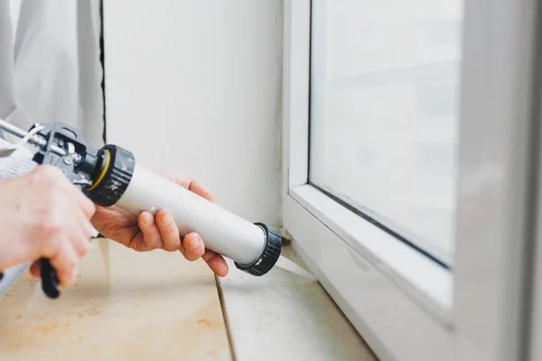 Manos de trabajador utilizando un tubo de silicona para la reparación de ventanas — Foto de Stock