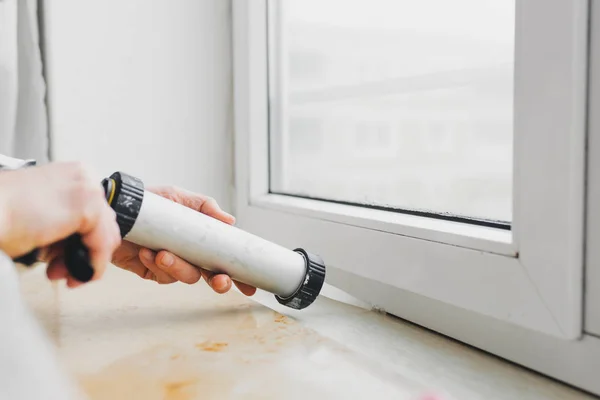 Manos de trabajador utilizando un tubo de silicona para la reparación de ventanas — Foto de Stock