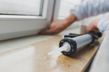 Ellerini pencerenin onarmak için silikon tüp kullanarak alt