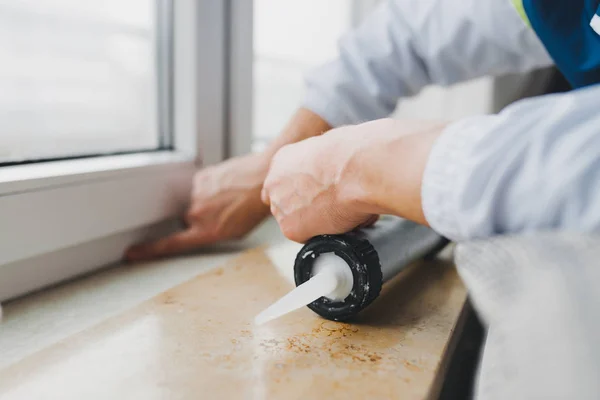 Manos de trabajador utilizando un tubo de silicona para la reparación de ventanas — Foto de Stock