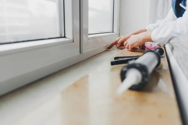 Manos de trabajador utilizando un tubo de silicona para la reparación de ventanas —  Fotos de Stock