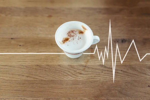 Tasse de café avec du lait sur la table en bois avec un graphique de battement de coeur — Photo