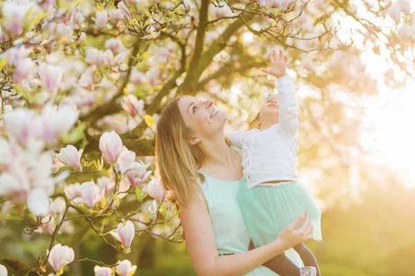 Joven madre con adorable hija en el árbol de flores —  Fotos de Stock