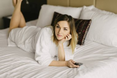 güzel kadın yatakta yatan ve otel odasında tv izle