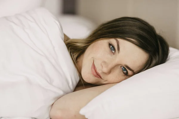 Hermosa mujer acostada en la cama en la habitación de hotel —  Fotos de Stock