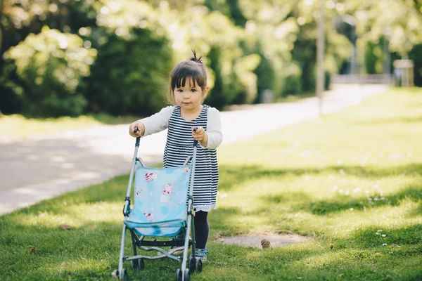 Schattig meisje speelt met een pop-kinderwagen — Stockfoto