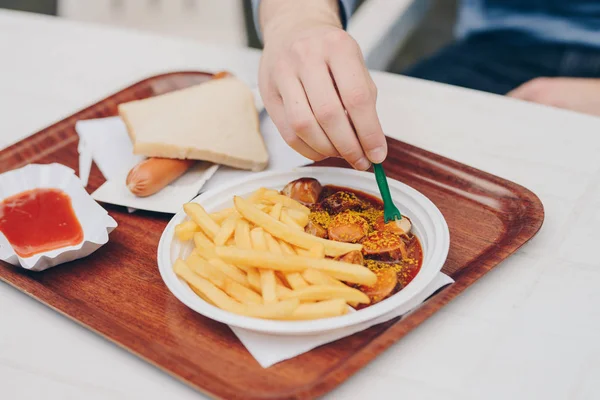 Currywurst ile açık bir patates kızartması yiyen bir adam elinde — Stok fotoğraf