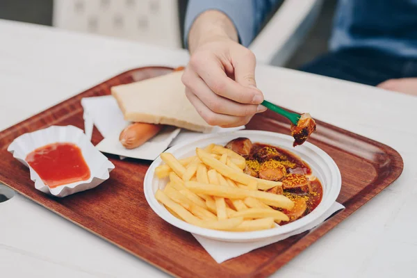 Currywurst ile açık bir patates kızartması yiyen bir adam elinde — Stok fotoğraf