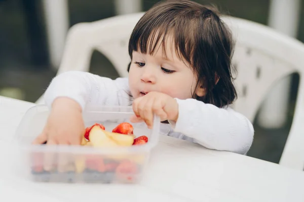 Aranyos kislány eszik egészséges snack, élelmiszer-tartályból. s — Stock Fotó
