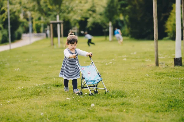 Schattig meisje speelt met een pop-kinderwagen — Stockfoto