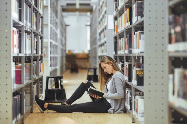 güzel kız öğrenci bir yüksek okul kütüphanesinde öğrenme 