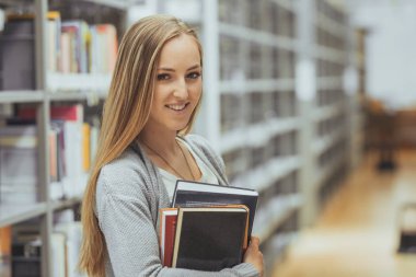 güzel kız öğrenci bir yüksek okul kütüphanesinde öğrenme 