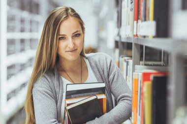 güzel kız öğrenci bir yüksek okul kütüphanesinde öğrenme 