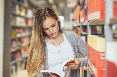 güzel kız öğrenci bir yüksek okul kütüphanesinde öğrenme 