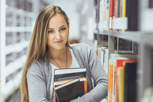 güzel kız öğrenci bir yüksek okul kütüphanesinde öğrenme 