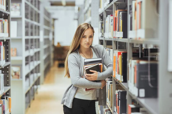 güzel kız öğrenci bir yüksek okul kütüphanesinde öğrenme 