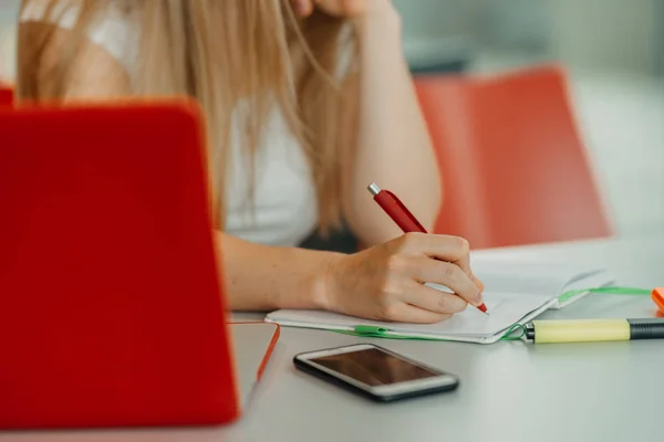 Händerna på kvinnliga skrivande på anteckningsboken i café med laptop, smartphone och kopp kaffe — Stockfoto