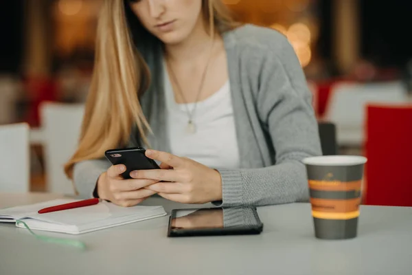 Händerna på kvinna som håller smartphone med tablett och kaffe i café — Stockfoto
