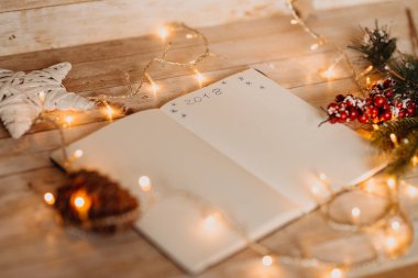 2018 açılan defter üzerinde yazılı. Noel ve yeni yıl süslemeleri ile ışık ahşap masa üzerinde Üstten Görünüm