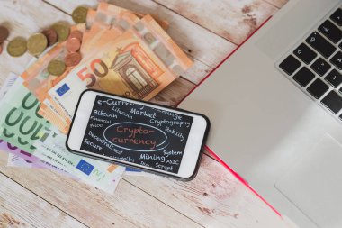 Cryptocurrency yerine her zamanki para. crypticurrency ikonografi üstten görünüm akıllı telefon ekran, euro banknot ve ahşap Danışma laptop parçası