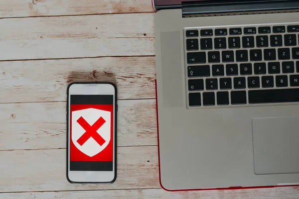 Internet insecure concept. top view of Insecure icon on smart phone screen and the part of  the laptop on wooden desk the part of the laptop on wooden desk — Stock Photo, Image