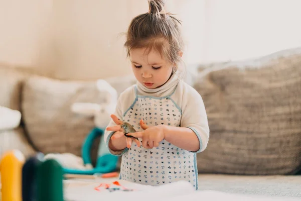 Toddler dziewczynka w rysunku fartuch zwraca palce w domu — Zdjęcie stockowe