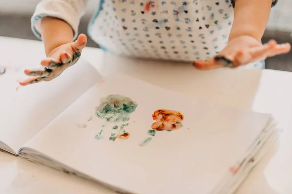 Kleinkind Mädchen in Schürze zeichnet Finger zu Hause, Nahaufnahme von — Stockfoto