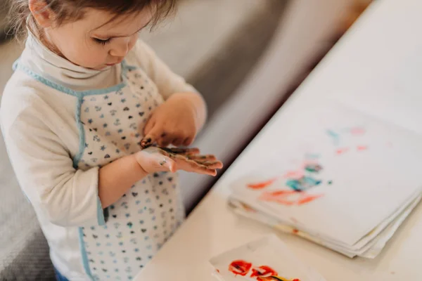 Kleinkind Mädchen in Schürze zeichnet Finger zu Hause, Nahaufnahme von — Stockfoto