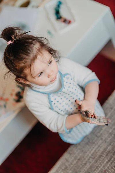Menina criança no desenho avental desenha dedos em casa — Fotografia de Stock