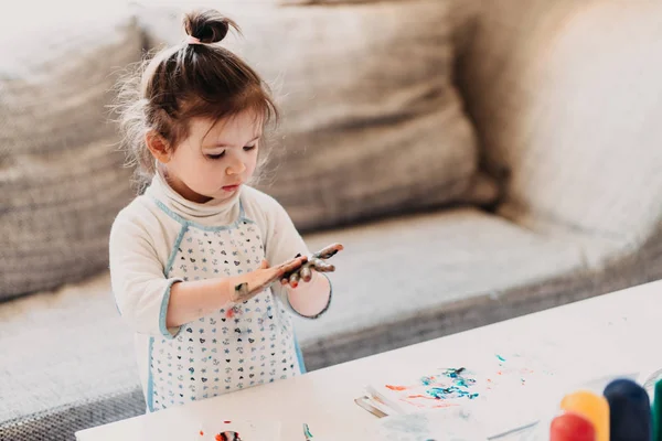 Kleinkind in Schürze zeichnet Finger zu Hause — Stockfoto