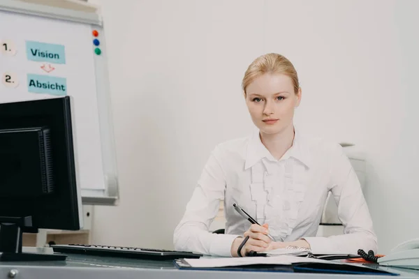 Schöne Frau im Büro arbeitet am Schreibtisch, schreibt im Planer — Stockfoto